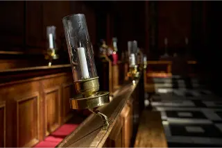 An unlit candle in a metal candle holder with a cylindrical glass shade at the Trinity College Chapel in Oxford, UK, on April 4, 2023 il negozio fantasma ambientazione foto licenza cc