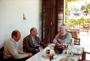 anniversai letterati Bill Davis, Rupert Bellville, and Ernest Hemingway dining at La Consula, 1959. immaigne pubblico dominio