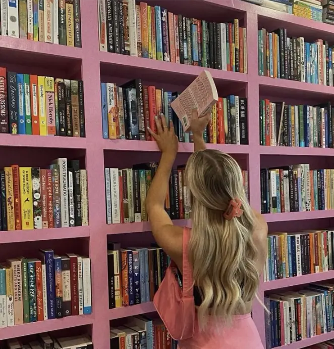 ragazza che prende libri da una libreria rosa