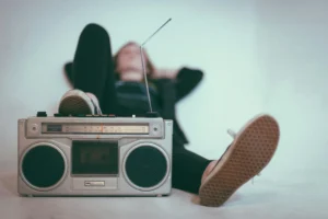Una radio in primo piano e una ragazza sdraiata sullo sfondo.