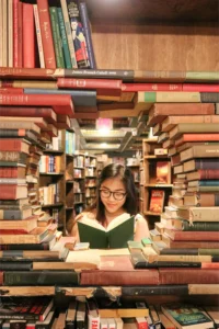 Una cornice rotonda fatta di libri rivela una ragazza che legge.
