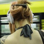 donna di spalle seduta in metro mentre ascolta audiolibri con cuffie