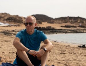 Graziano Bracchi sduto su una spiaggia autore di Armomia  disimparare