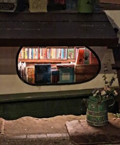 Foto dell'interno in cui si vede un oblò e dei libri e il canale fuori