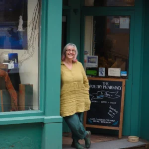 foto della fondatrice di POetry Pharmacy , Deborah Alma appoggiata alla etrina del negozio