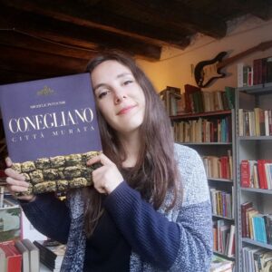 Caterina Mognol con un libro in mano dentro la libreria del gattile