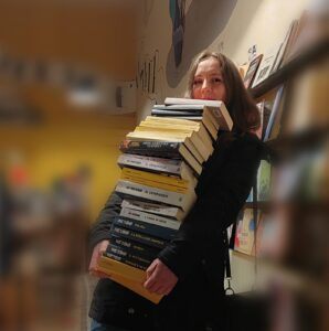 Caterina Mognol con una pila di libri in mano