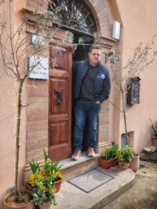 Marco Pontoni sulla porta con a fianco degli ulivi