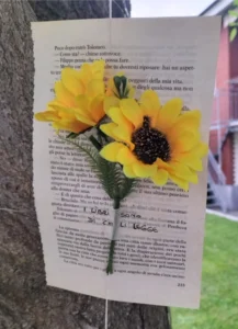 un foglio appoggiato a un albero con un girasole