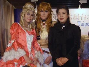 Due cosplayer di Maria Antonietta e Lady Oscar e, a destra, l'autrice del manga Riyoko IkedaDi Rico Shen, CC BY-SA 4.0