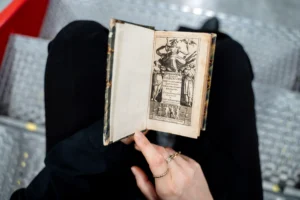 una persona seduta con un libro antico sulle ginocchia 