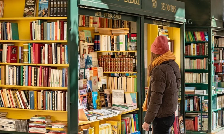 libri esposti in via Po a Toiro in una bancarella dell'usato con una ragazza che li guarda vestita da stagione invernale