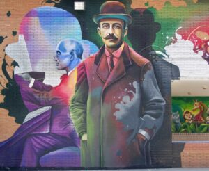 Murale di Lalo Luque (Lalone) del 2021 nel cortile della scuola Manuel de Falla, al numero 16 di Calle José Palanca, quartiere El Torcal, Malaga, Spagna. Il murale raffigura il musicista Manuel de Falla in due situazioni diverse, in piedi con un cappello e un soprabito e seduto al pianoforte.