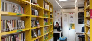 interni del bus con scaffali gialli e una bibliotecaria